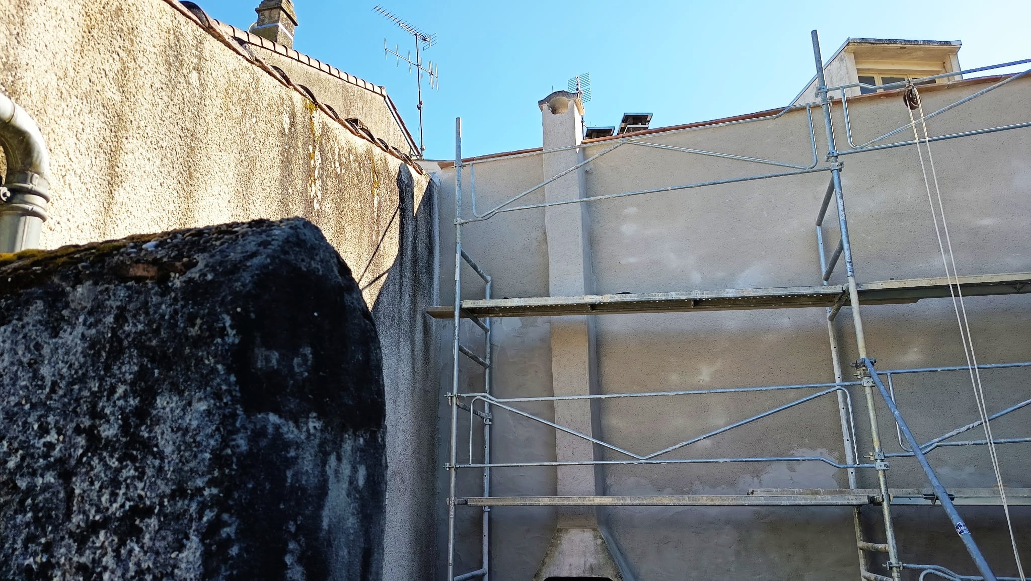 Échafaudage métallique installé devant la façade d'un immeuble en cours de rénovation sous un ciel bleu.